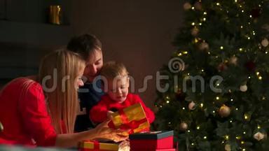 在圣诞节，爸爸妈妈和儿子在<strong>家</strong>里打开礼物，坐在圣诞内部<strong>的</strong>沙发上。 <strong>温馨</strong>舒适<strong>的家</strong>
